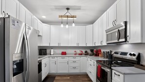 Una cocina moderna con armarios blancos, electrodomésticos de acero inoxidable y suelo de madera.