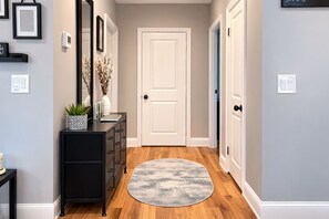 A hallway with a round rug, a black dresser, a white door, and framed pictures on the wall. - Stylish & Cozy Atlanta Home Near BeltLine & Downtown (Atlanta)