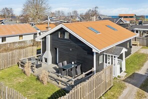 A modern house with a sloped roof, a deck with outdoor furniture, and a fenced yard. - Lovely holiday home near Hasmark Beach (Otterup)