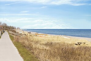 Une promenade en bord de mer avec un banc, une table de pique-nique et un bateau sur la plage.