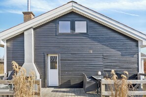 Une cabane en bois avec un toit à pignon, une cheminée et une porte.
