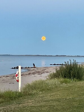 A beach with a lifebuoy, a person fishing, and a clear sky. - Lovely holiday home near Hasmark Beach (Otterup)