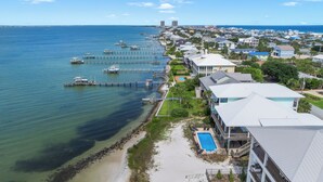 A coastal residential area with houses, a dock, and a swimming pool. - Baywatch Beach House | Private Pool | Beach Service Included | Dog Friendly (Pensacola Beach)