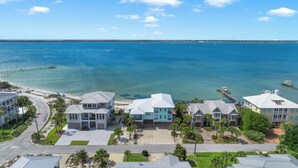 A coastal residential area with houses, a pier, and a clear view of the ocean. - Baywatch Beach House | Private Pool | Beach Service Included | Dog Friendly (Pensacola Beach)