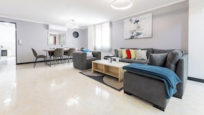 A modern living room with a grey sofa, a coffee table, and a dining area with chairs and a table. - Large Hidden Gem in Poblado with A/C and gym. Steps from Provenza / Lleras. (Medellín)