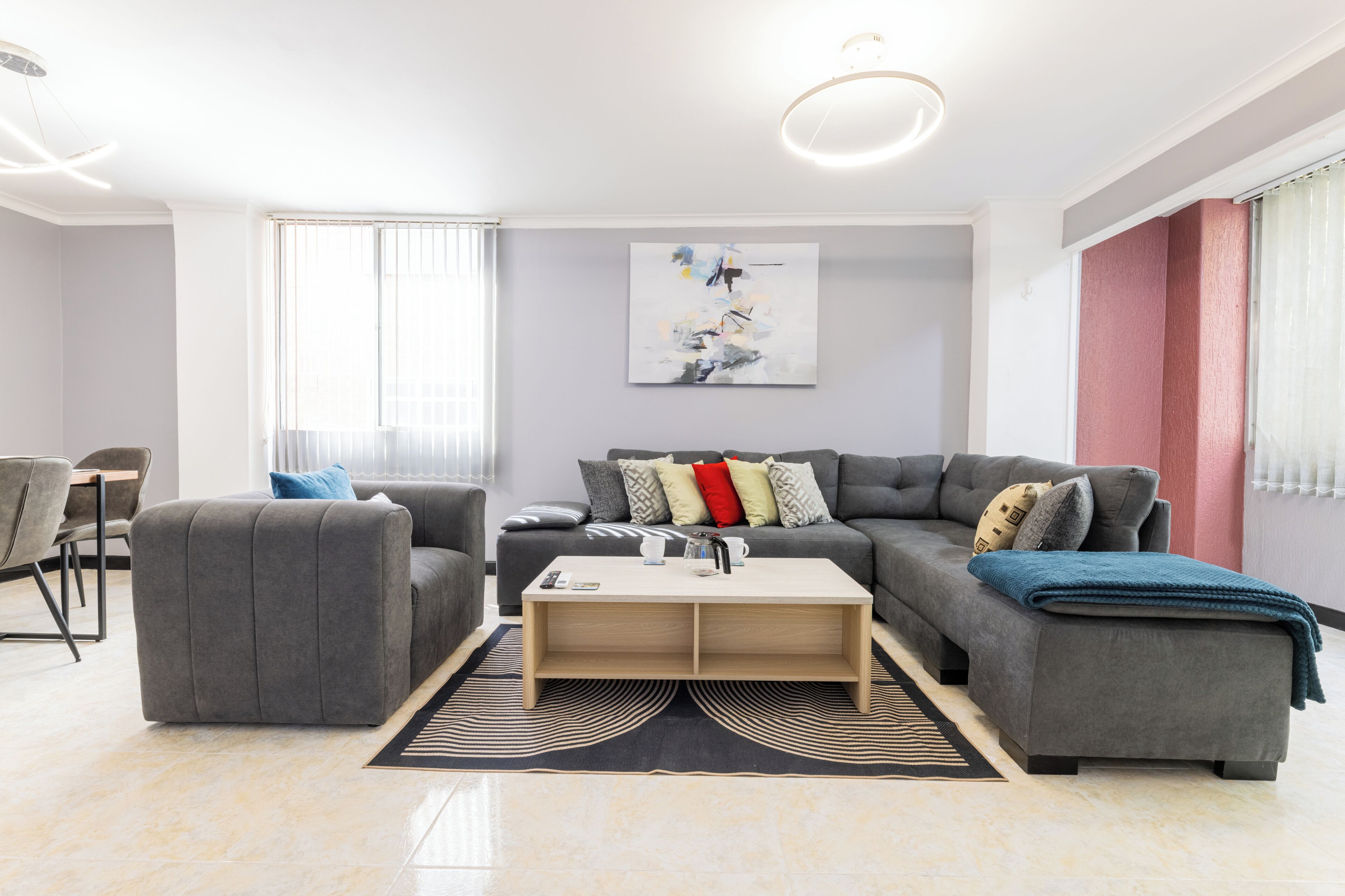A modern living room with a sofa, ottoman, coffee table, and artwork on the wall.
