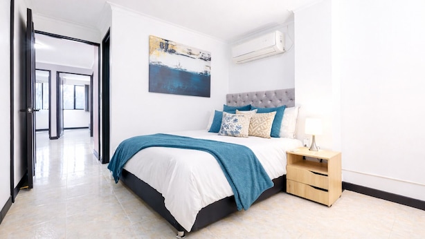 A modern bedroom with a bed, bedside table, and an air conditioning unit. - Large Hidden Gem in Poblado with A/C and gym. Steps from Provenza / Lleras. (Medellín)