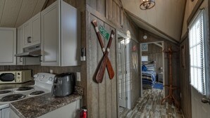 Una cocina con armarios blancos, un tostador, una cafetera y unas paletas de madera en la pared.