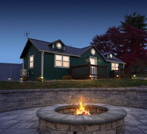 A two-story house with a fire pit in the foreground.