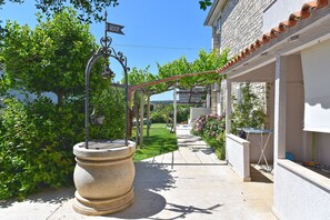 A pathway leading to a building with a stone barrel, a pergola with vines, and a street sign indicating the year 2007. - Apartment 810/199712 (Istria - Medulin), 600m from the beach (Medulin)