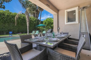 An outdoor dining area with wicker furniture, a pool, and a view of the backyard. - Get extra festival day free, walking distance, Pool-Large-Home (Indio)