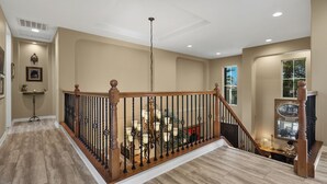 Un interior espacioso con una escalera de madera, un candelabro y vistas al exterior.