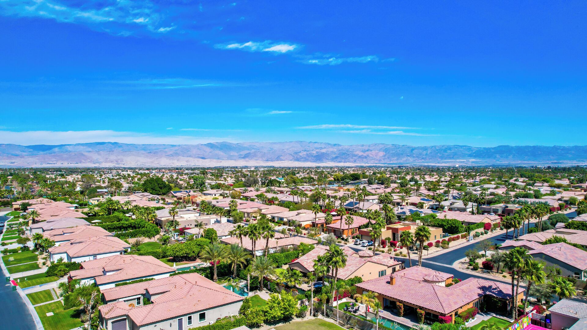 Zona residencial con casas, palmeras y montañas al fondo.