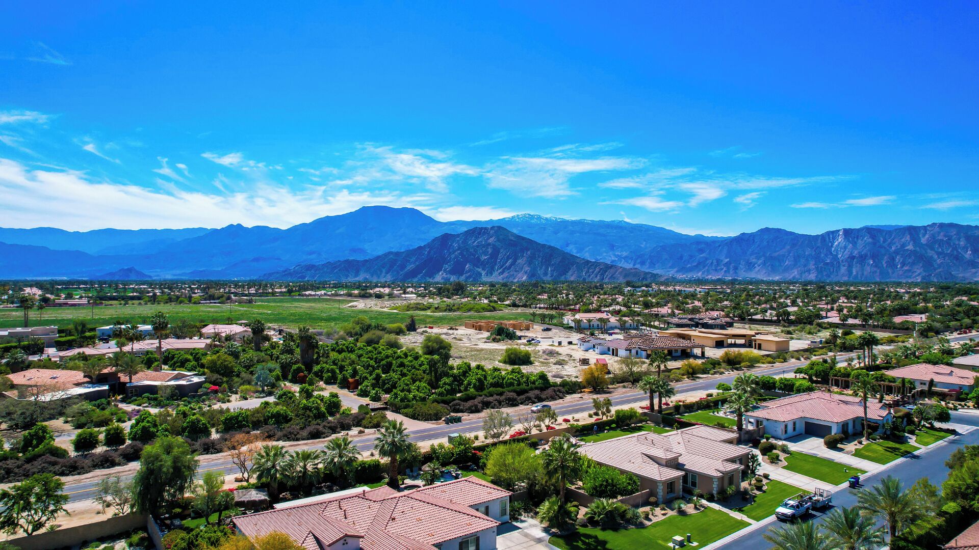 A residential area with houses, roads, and mountains in the background.