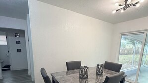 Un espace repas moderne comprenant une table rectangulaire, quatre chaises et deux porte-bougies décoratifs.