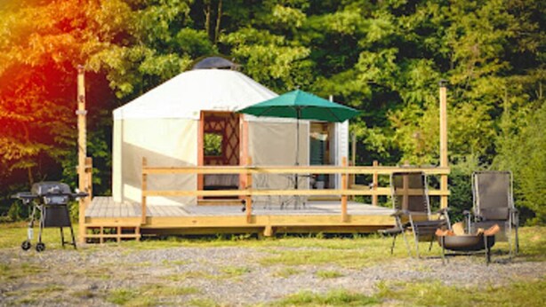 A yurt with a wooden deck, a green umbrella, and outdoor seating. - OffGrid Glamping Yurt with mountain views on Doe River & Historic Tweetsie Trail (Roan Mountain)