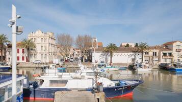 Un port de plaisance avec des bateaux amarrés, un bâtiment à l’architecture classique et un ciel dégagé.