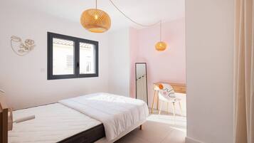 Une chambre à coucher comprenant un lit, un bureau, une chaise, un miroir et deux lampes suspendues.