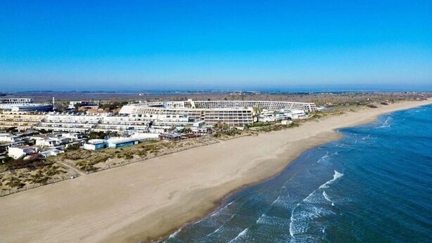 Un hotel sulla costa con diversi edifici, una spiaggia sabbiosa e l'oceano.