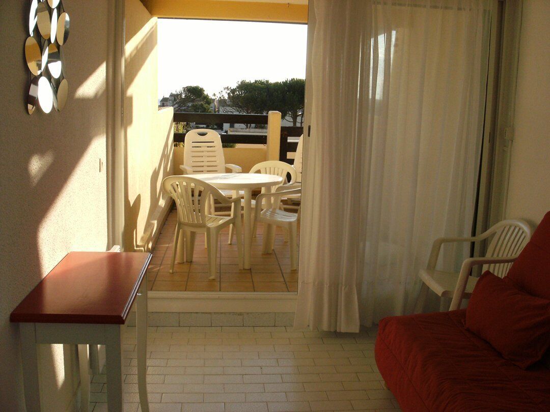 Un balcon avec une table et des chaises, un canapé rouge et une vue sur l’extérieur.