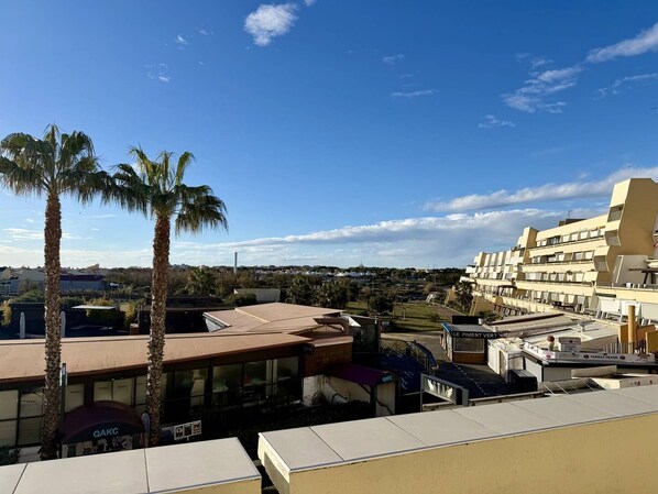 A hotel with a flat roof, palm trees, and a view of a cityscape. - Port Nature Apartment 476 – 2 people (AGDE)