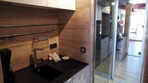 Eine moderne Küche mit schwarzem Arbeitsplatz, weißen Schränken und einer Glastür zum Essbereich.