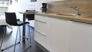 A modern kitchen with white cabinets, a wooden countertop, a stainless steel sink, and a coffee maker. - POPPY - Port Nature Studio 461 - Luxury - 2 people (AGDE)