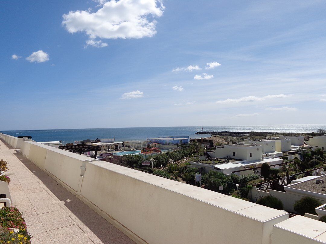 Una zona residencial costera con vistas despejadas al mar, un paseo marítimo pavimentado y diversos edificios.