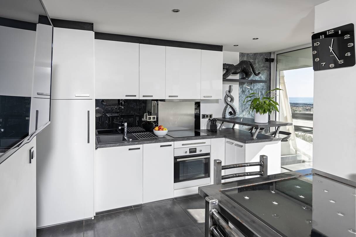 Een moderne keuken met witte kastjes, een zwart aanrecht en uitzicht op de stad.