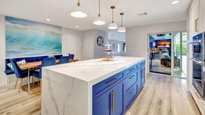 Una cocina moderna con una isla grande, armarios azules e iluminación colgante.