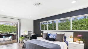 Un dormitorio moderno con una cama grande, un escritorio y vistas al verde exterior.