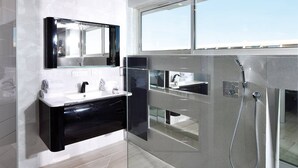 Et moderne badeværelse med en brusekabine i glas, et sort toiletbord og et stort spejl.