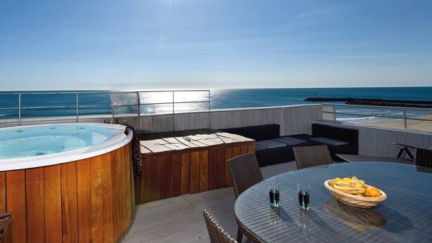 En tagterrasse med jacuzzi, siddeområde og et bord med frugt.