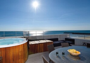 Eine Dachterrasse mit Whirlpool, Sitzgelegenheit und einem Tisch mit Obst.