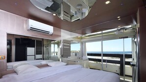 Et moderne skibskabin med en stor seng, et sminkebord og en balkon med udsigt over havet.