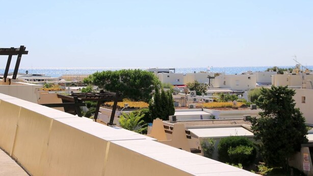 Una zona residenziale sulla costa, con edifici, una pergola e vista sul mare.