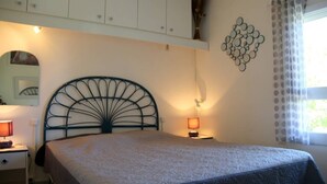 Una camera da letto con un letto, un comodino, una lampada e una finestra con tende.