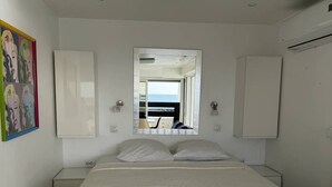 A bedroom with a bed, a mirror, a painting, and an air conditioning unit. - LA BELLE VUE - Studio Port Nature Studio 115s with garage - Luxe - Seafront - 2 people (AGDE)