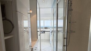 A modern bathroom with a washing machine, glass shower enclosure, and a view of the sea. - LA BELLE VUE - Studio Port Nature Studio 115s with garage - Luxe - Seafront - 2 people (AGDE)