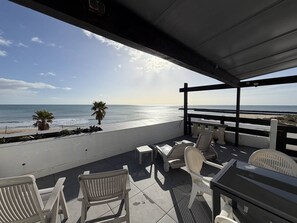 A covered outdoor seating area with a view of the beach and ocean. - LA BELLE VUE - Studio Port Nature Studio 115s with garage - Luxe - Seafront - 2 people (AGDE)