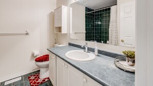 Een badkamer met een wit toilet, een wastafel met een spiegel erboven en een rode badmat.
