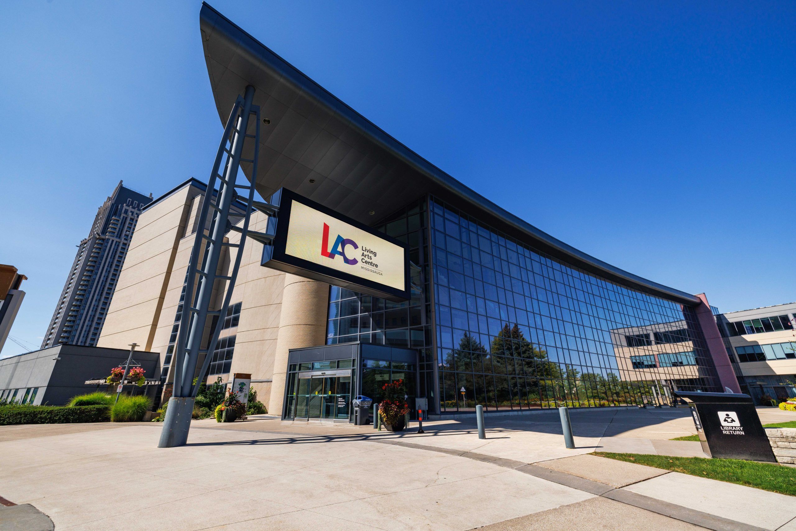 A modern building with a large glass facade, a prominent sign reading 'Living Center,' and a wheelchair accessibility sign.