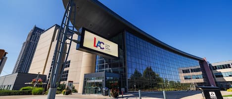 Un edificio moderno con una amplia fachada de vidrio, un cartel llamativo que dice 'Living Center' y el símbolo de accesibilidad para sillas de ruedas.