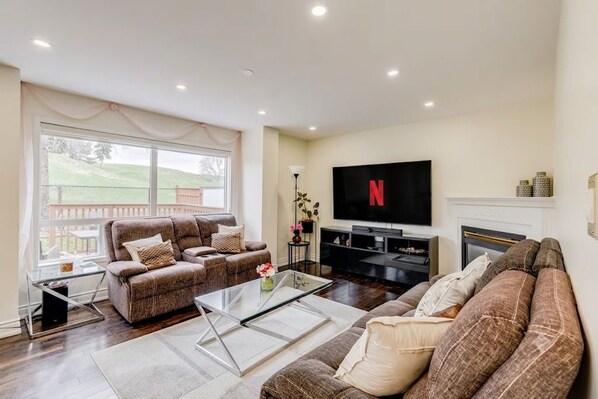 A living room with a sofa set, a coffee table, a flat-screen TV, and a fireplace.