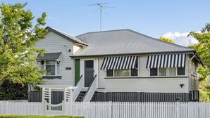 Une maison à deux étages avec une clôture blanche en bois, un porche à l’avant et un garage.