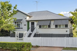 A two-story house with a white picket fence, a front porch, and a garage.
