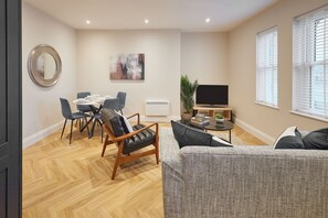 Uma sala de estar moderna com área de jantar, televisão de tela plana e um espelho grande.