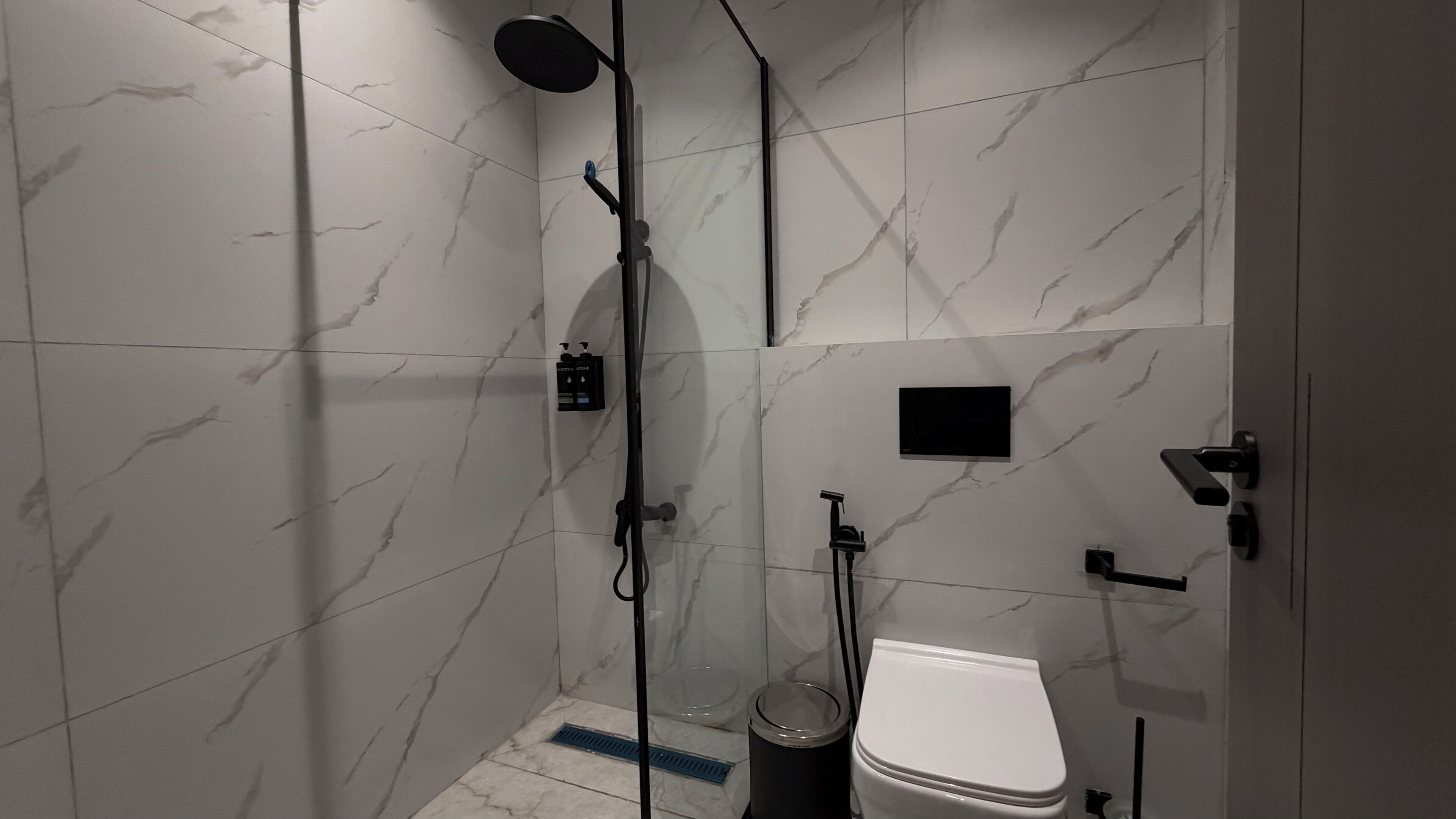 Ein modernes Badezimmer mit einer Duschkabine, einer Toilette und einem kleinen Waschbecken.