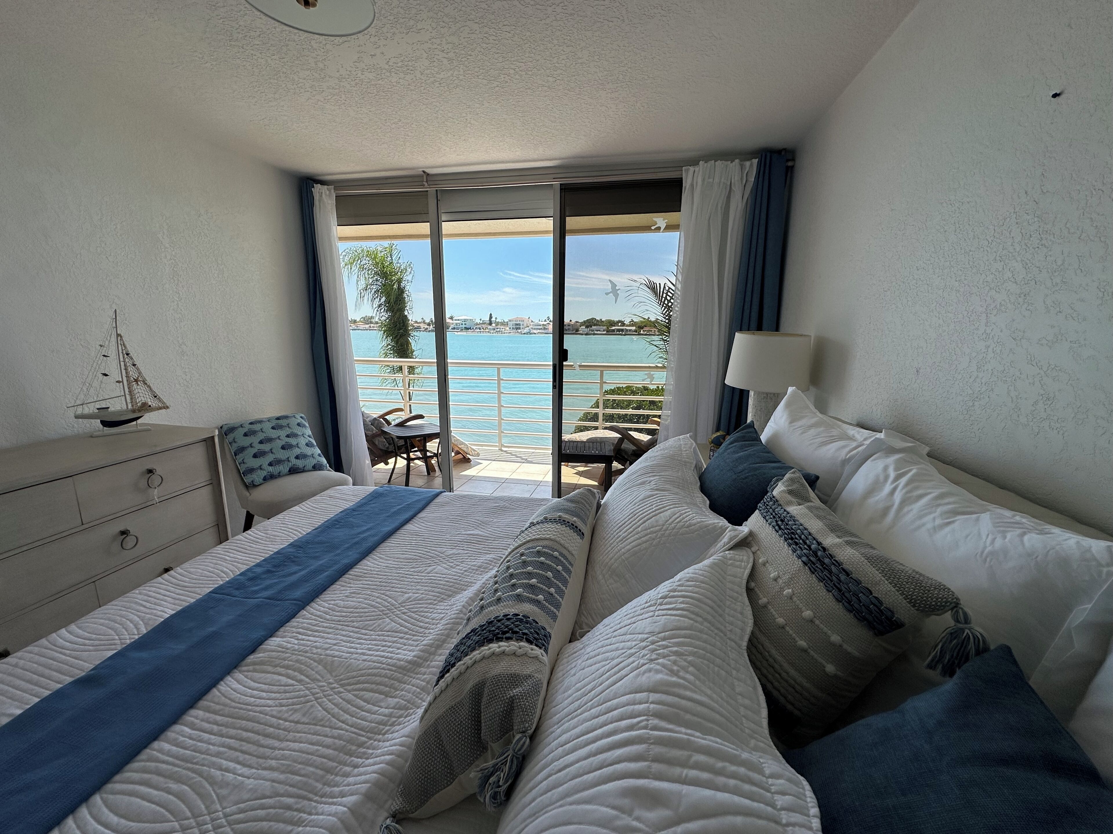 Una habitación de hotel con cama, cómoda, silla, mesa y vista al mar.