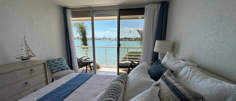 Una habitación de hotel con cama, cómoda, silla, mesa y vista al mar.